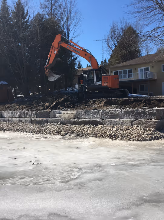 Excavator placing rip rap stone along Kawartha Lakes shoreline